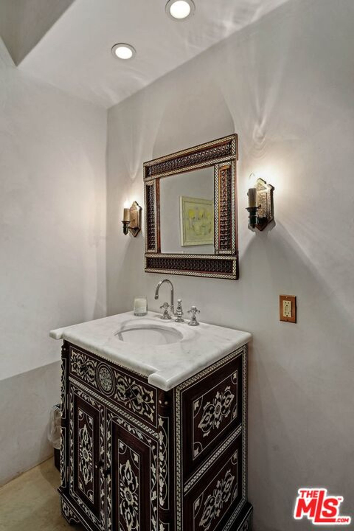 Elegant powder room featuring an ornate vanity with intricate detailing and a marble countertop.