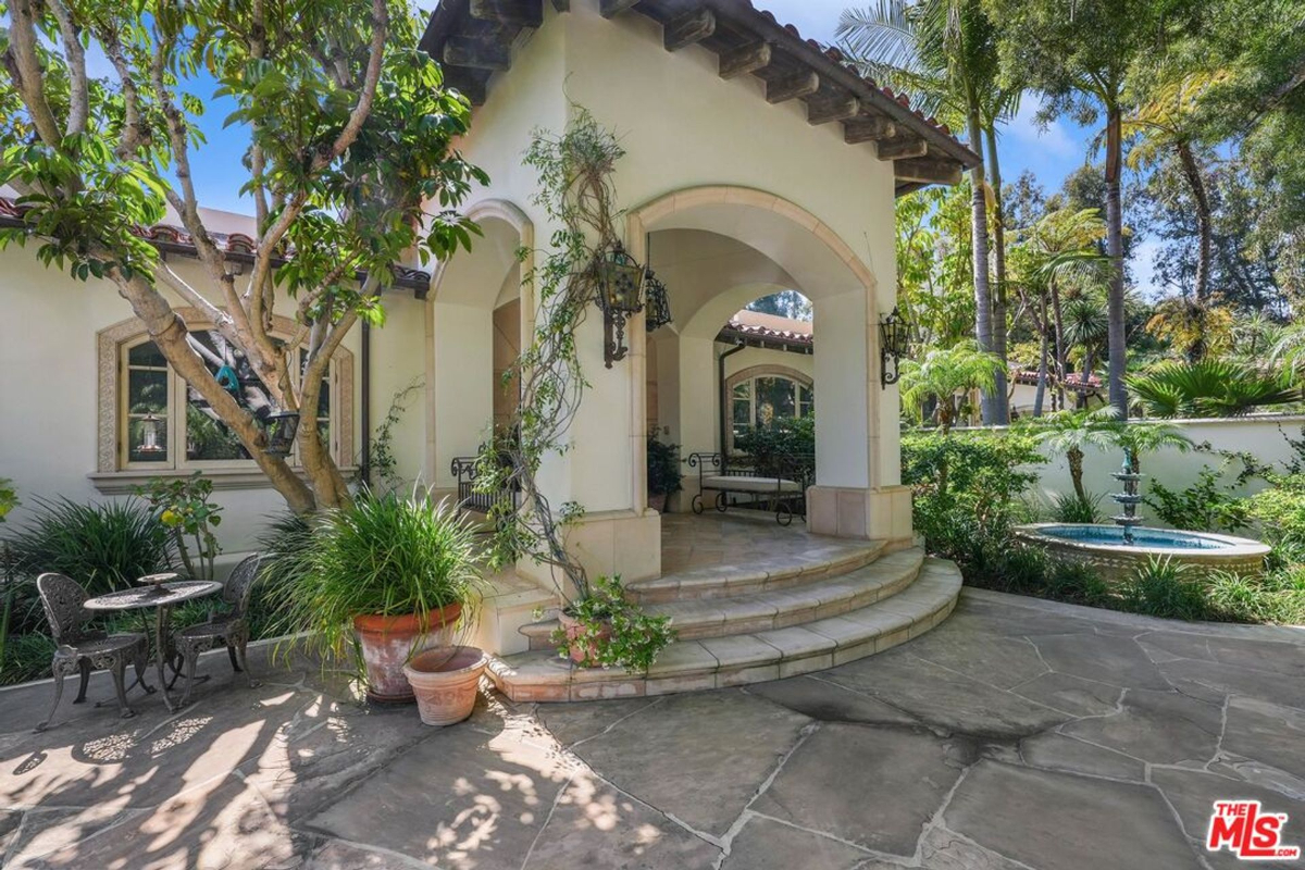 Charming patio with a stone fountain and vine-covered archways.