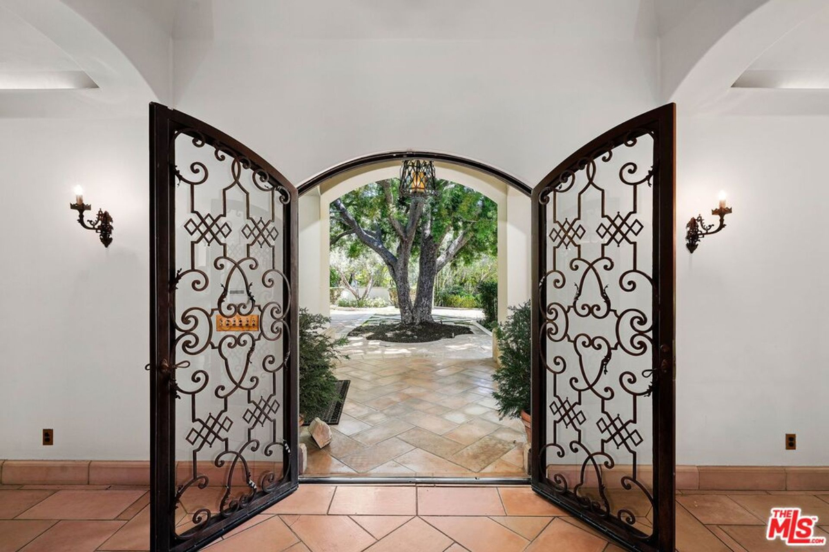 Ornate double doors opening to a view of the courtyard and a beautiful mature tree.