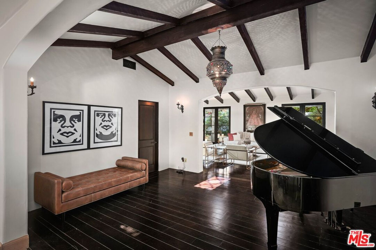 Sophisticated living space featuring dark wood floors, exposed beams, and a grand piano.