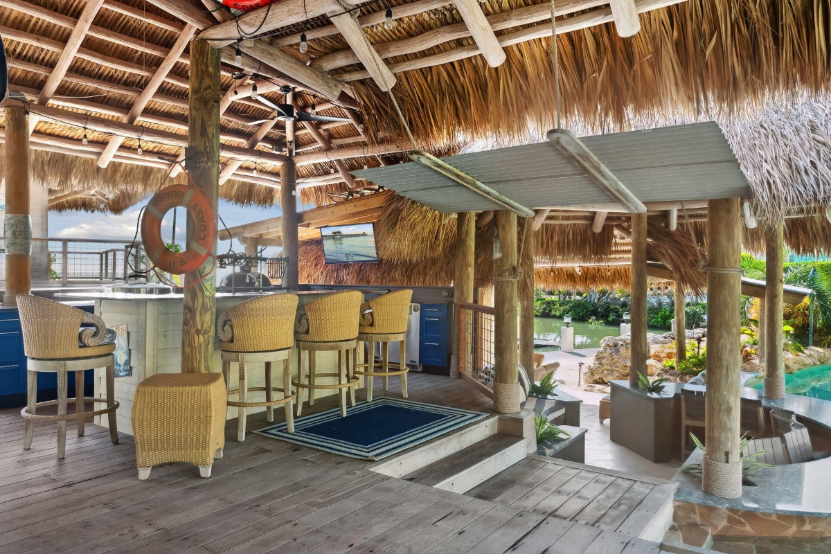 A thatched tiki hut with a full bar and cozy seating creates the ultimate tropical retreat.