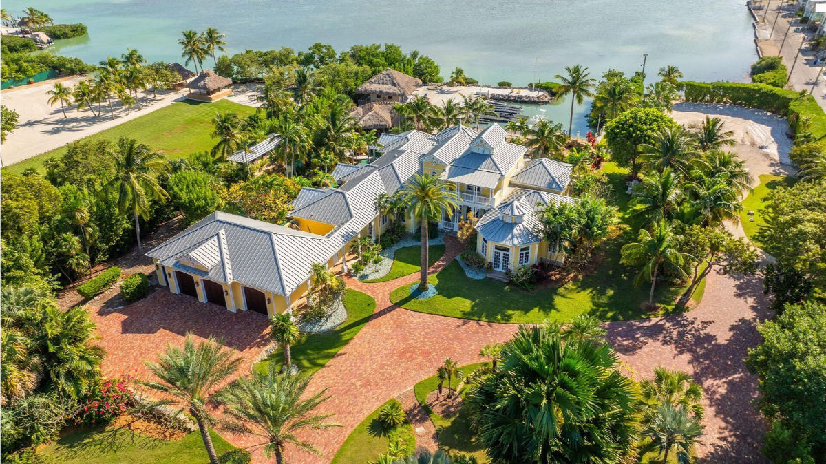 Aerial view showcases a sprawling coastal estate nestled along the waterfront.