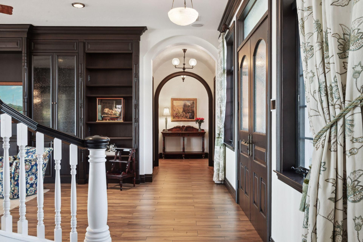 Entryway with elegant arches, rich wood accents, and natural light filtering through floral curtains.