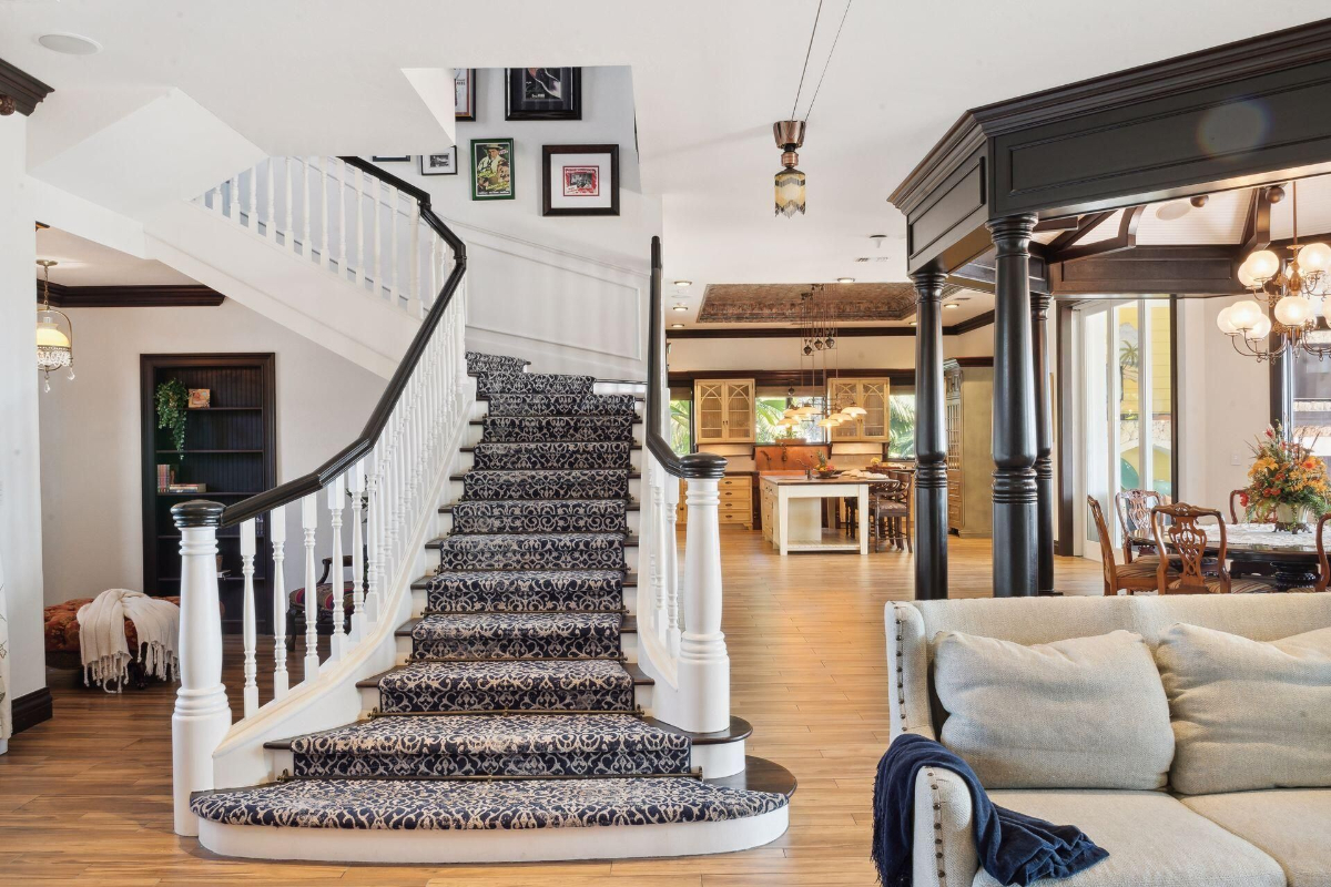 A gracefully curved staircase leads to the upper level, complementing the warm tones of the open-concept kitchen and dining area.