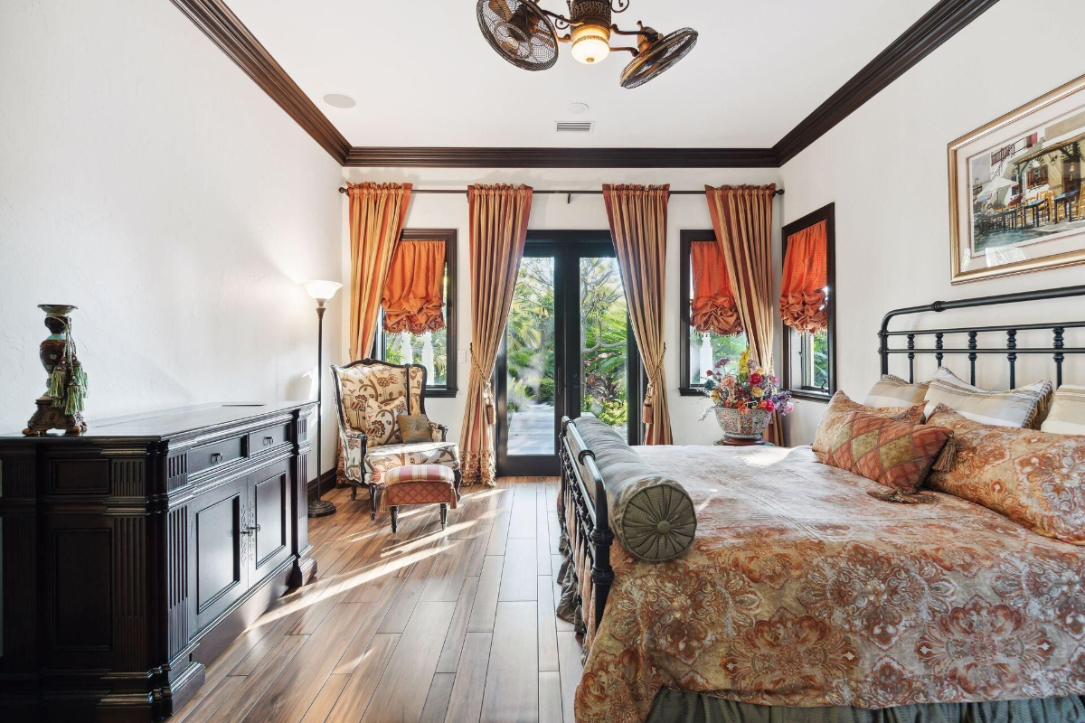 Richly patterned curtains and bedding complement the warmth of the hardwood floors, creating an inviting and elegant bedroom retreat.