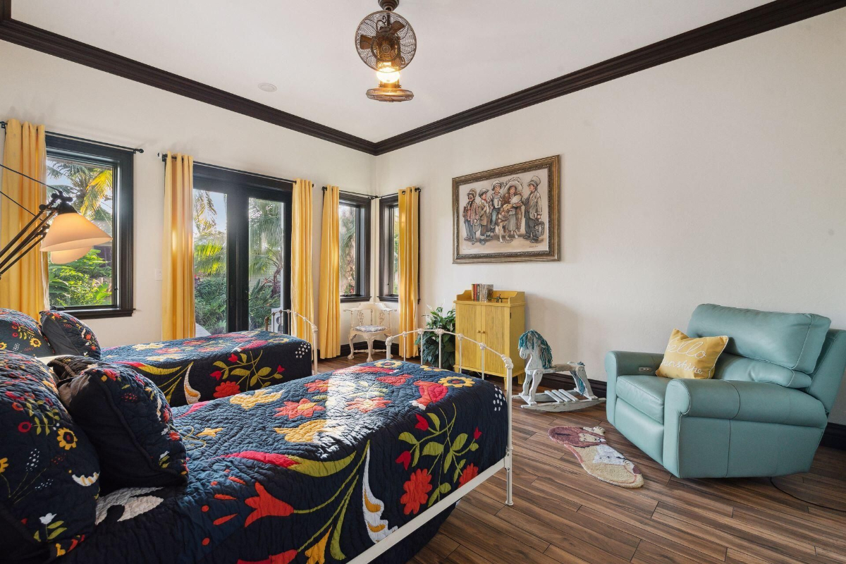 Bright yellow curtains and colorful floral bedding add a cheerful touch to this charming twin bedroom with garden views.