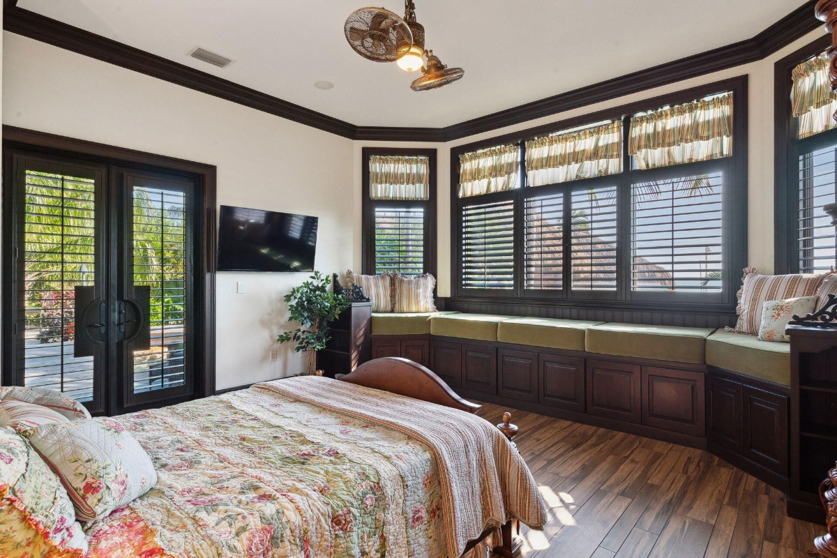 A cozy bedroom with charming floral bedding and a custom window seat invites relaxation while offering serene garden views.