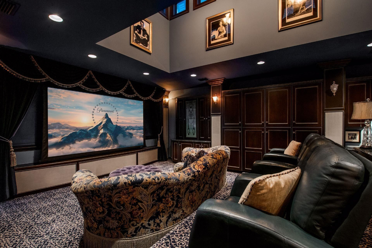 Home theater offers a cinematic escape with its oversized screen, plush seating, and custom paneling under an ambient-lit ceiling.