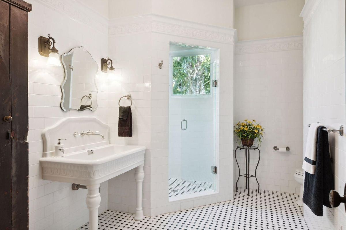 Bathroom showcases elegant tilework, a pedestal sink, and a walk-in shower with lush garden views.