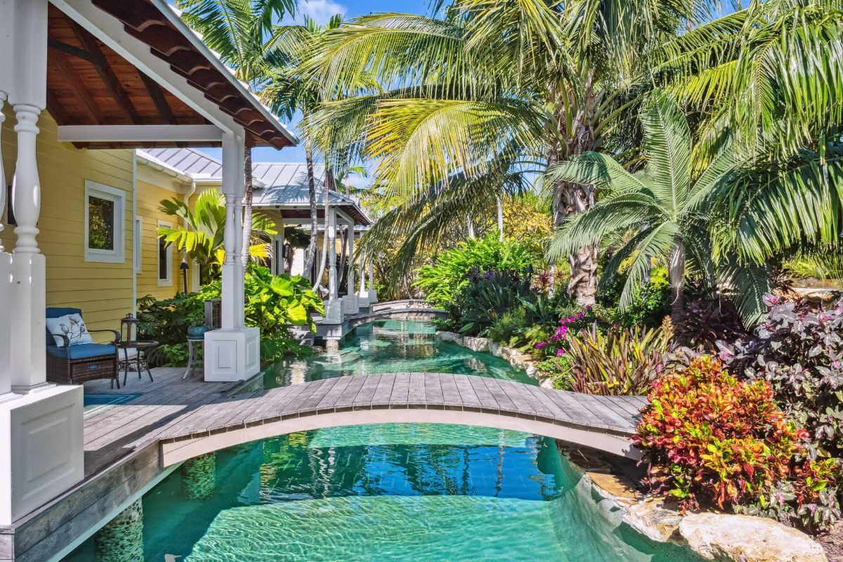 Tropical lagoon winds through lush gardens, accented by a charming wooden bridge and vibrant greenery.