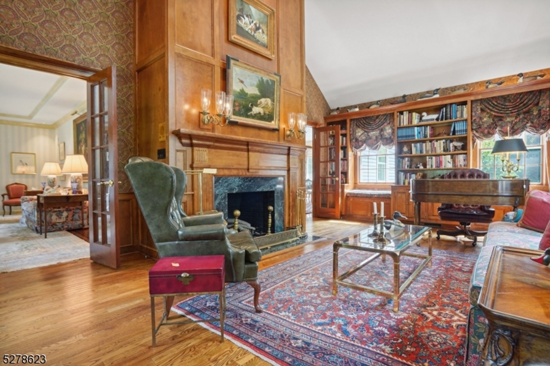 Sophisticated library featuring rich wood paneling, a grand fireplace, built-in bookshelves, and elegant furnishings.