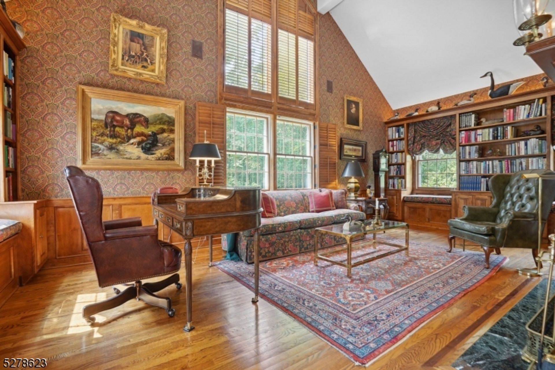 Refined study showcasing floor-to-ceiling windows, intricate wallpaper, built-in shelves, and classic furnishings.