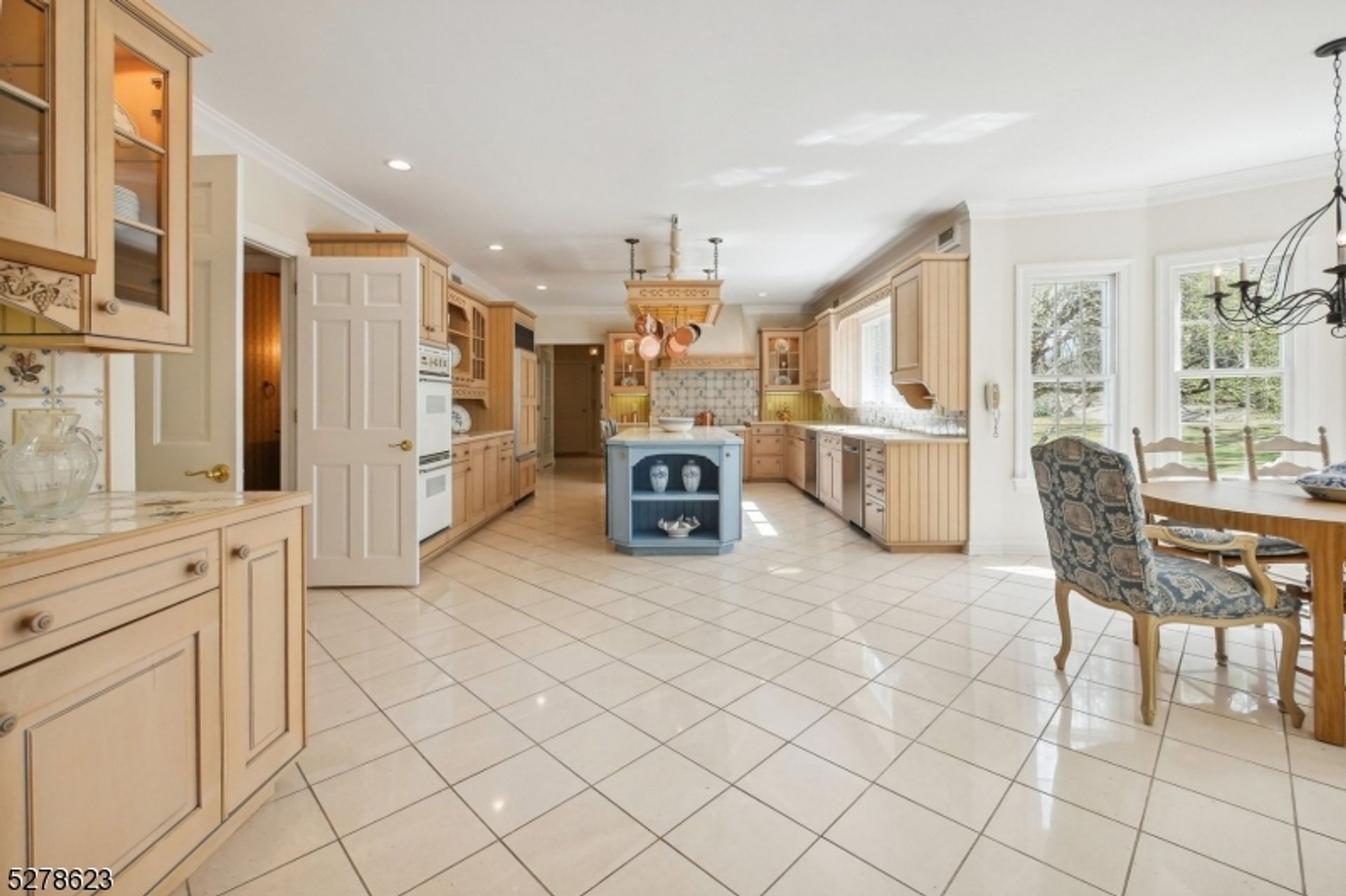 Bright and spacious kitchen featuring custom cabinetry, a central island, and an inviting breakfast area with garden views.