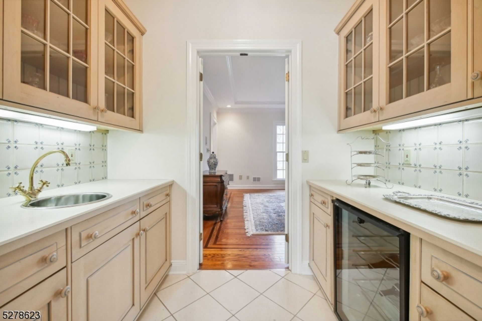 Compact butler's pantry with a built-in wine cooler, tiled backsplash, and glass-front cabinetry.