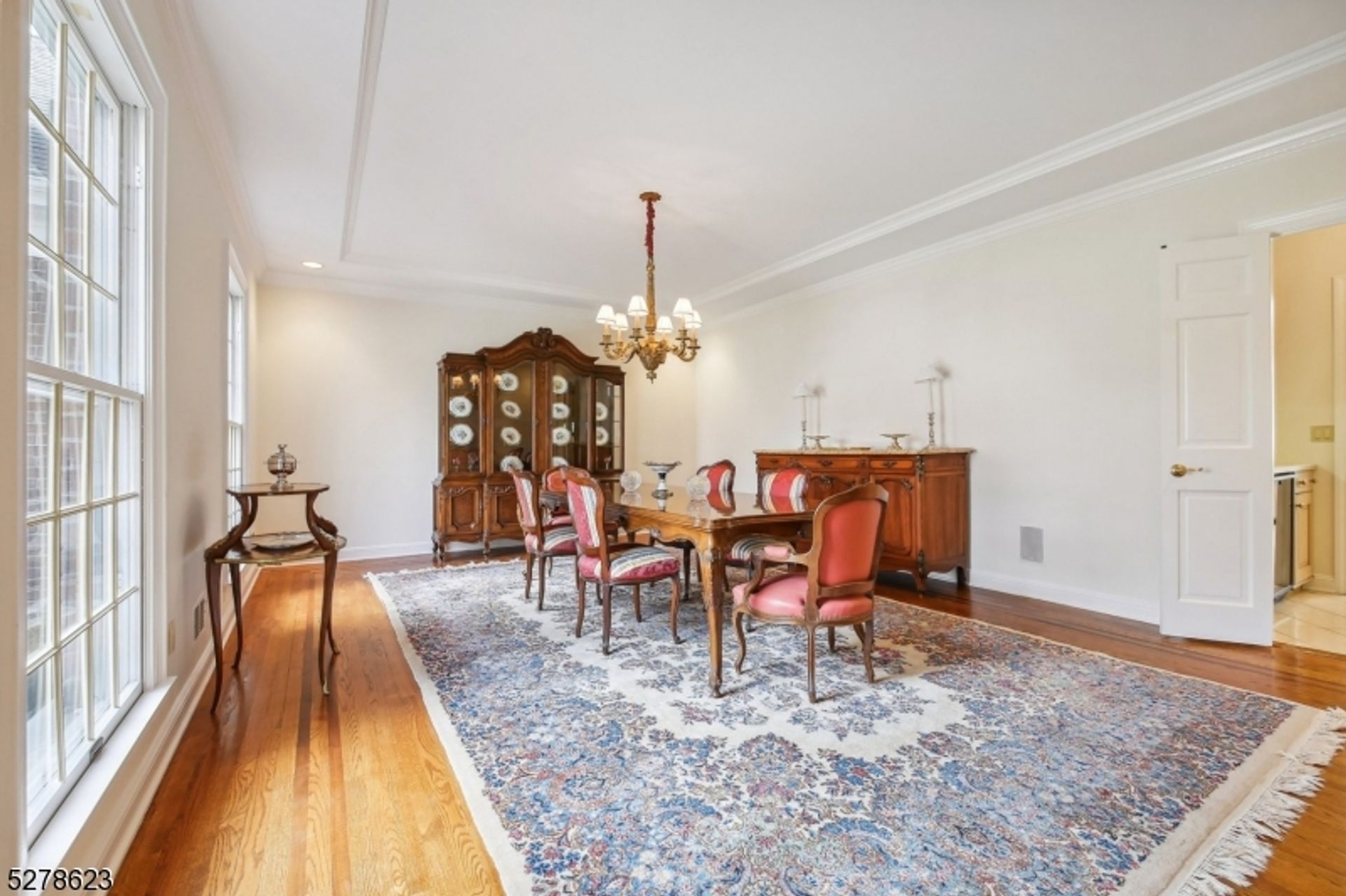 Formal dining room with classic crown molding, large windows, and a statement chandelier.