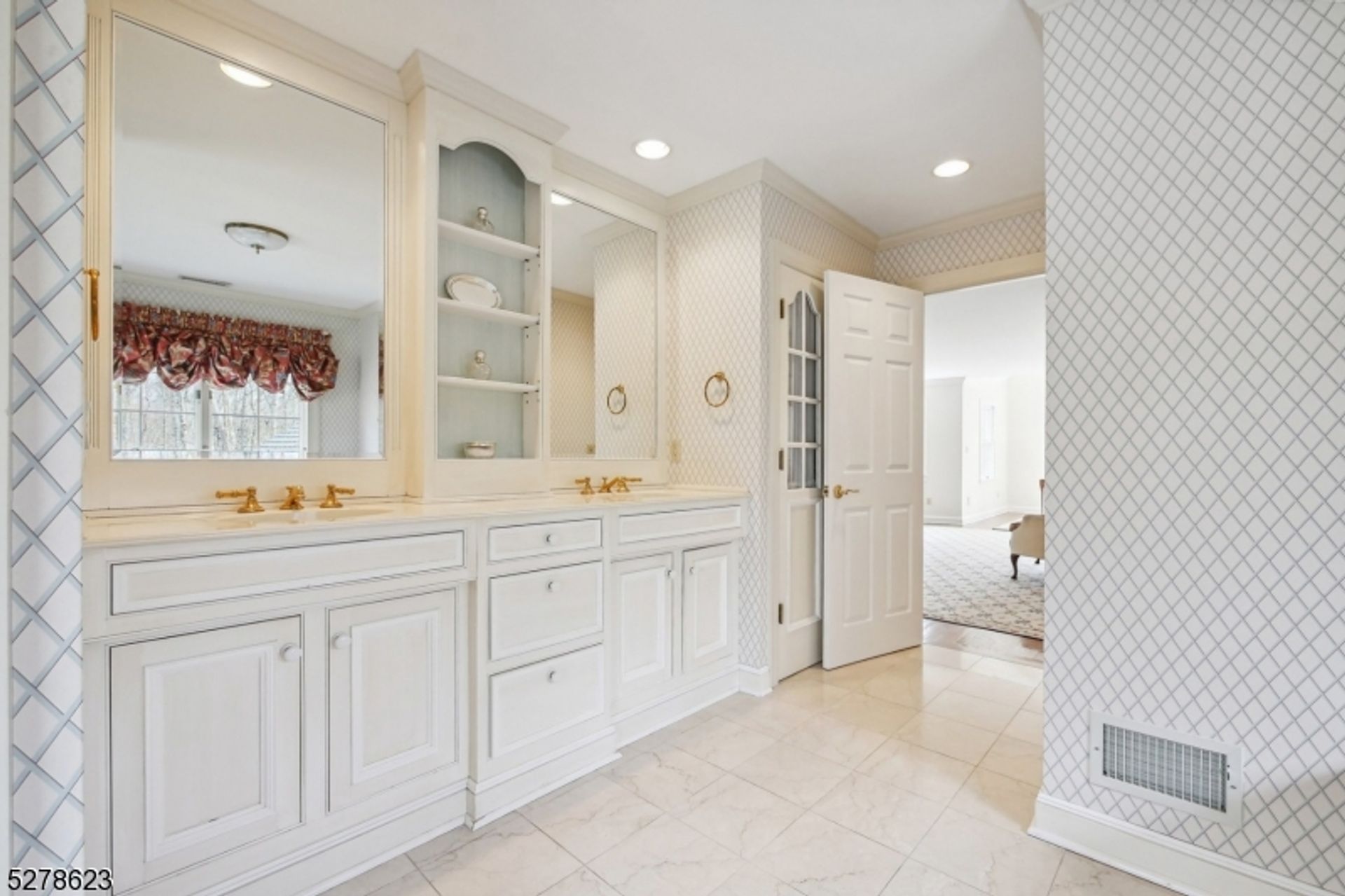 Bathroom features a double vanity with gold fixtures and built-in shelving for added storage.