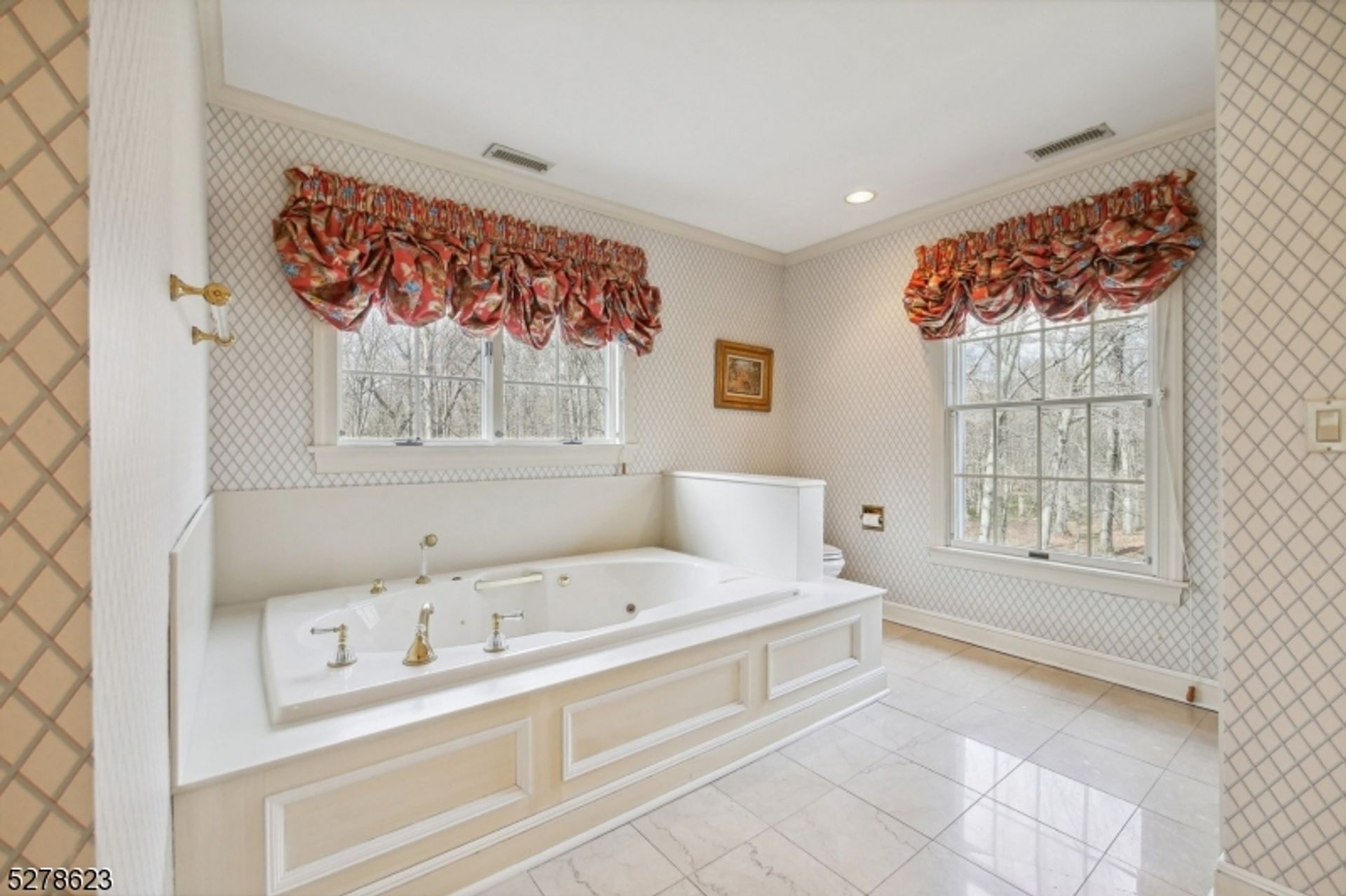 Bathroom showcases a large built-in soaking tub, patterned wallpaper, and bright windows with floral valances.