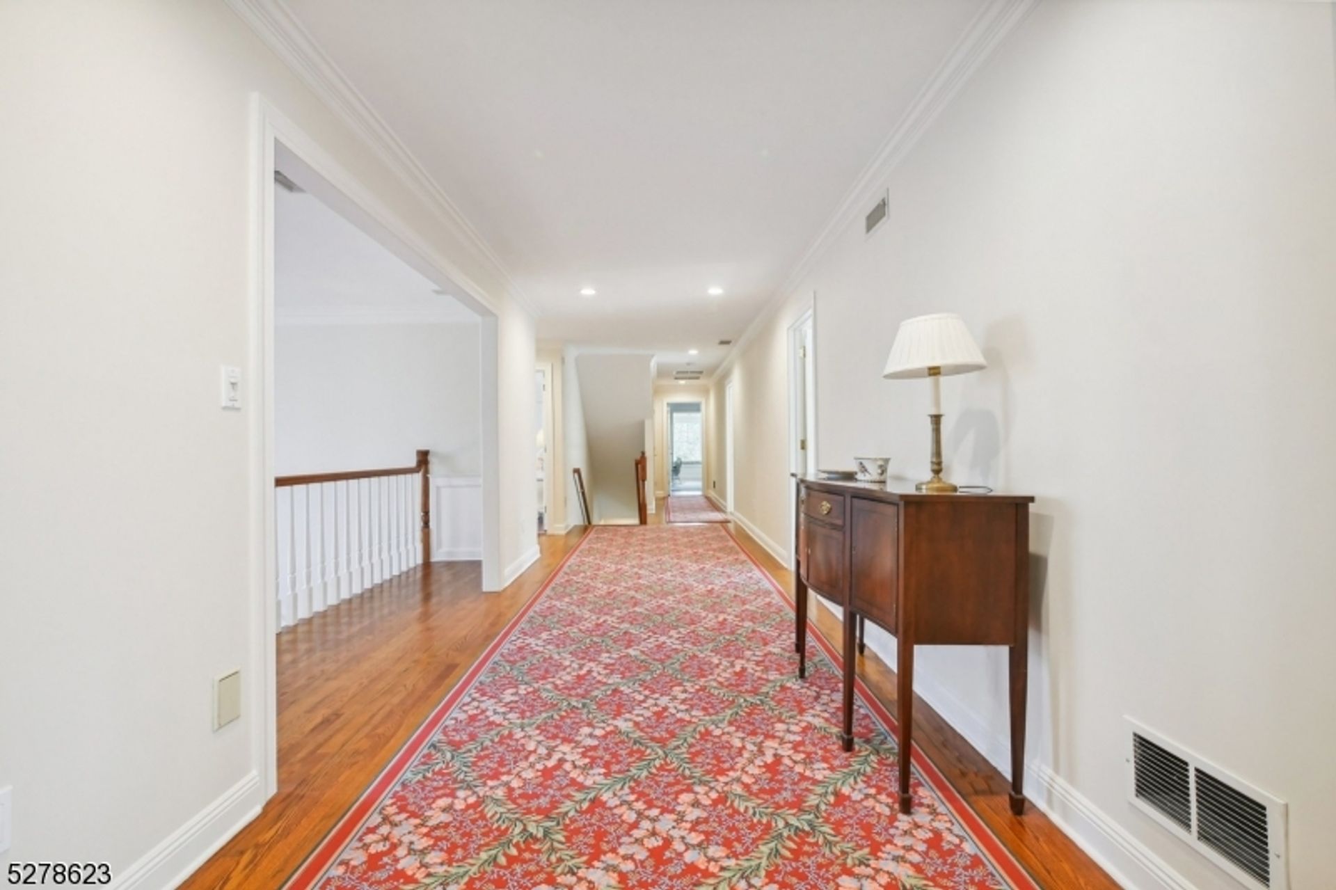 Bright hallway with a floral red runner, elegant side table, and a seamless flow between spaces.