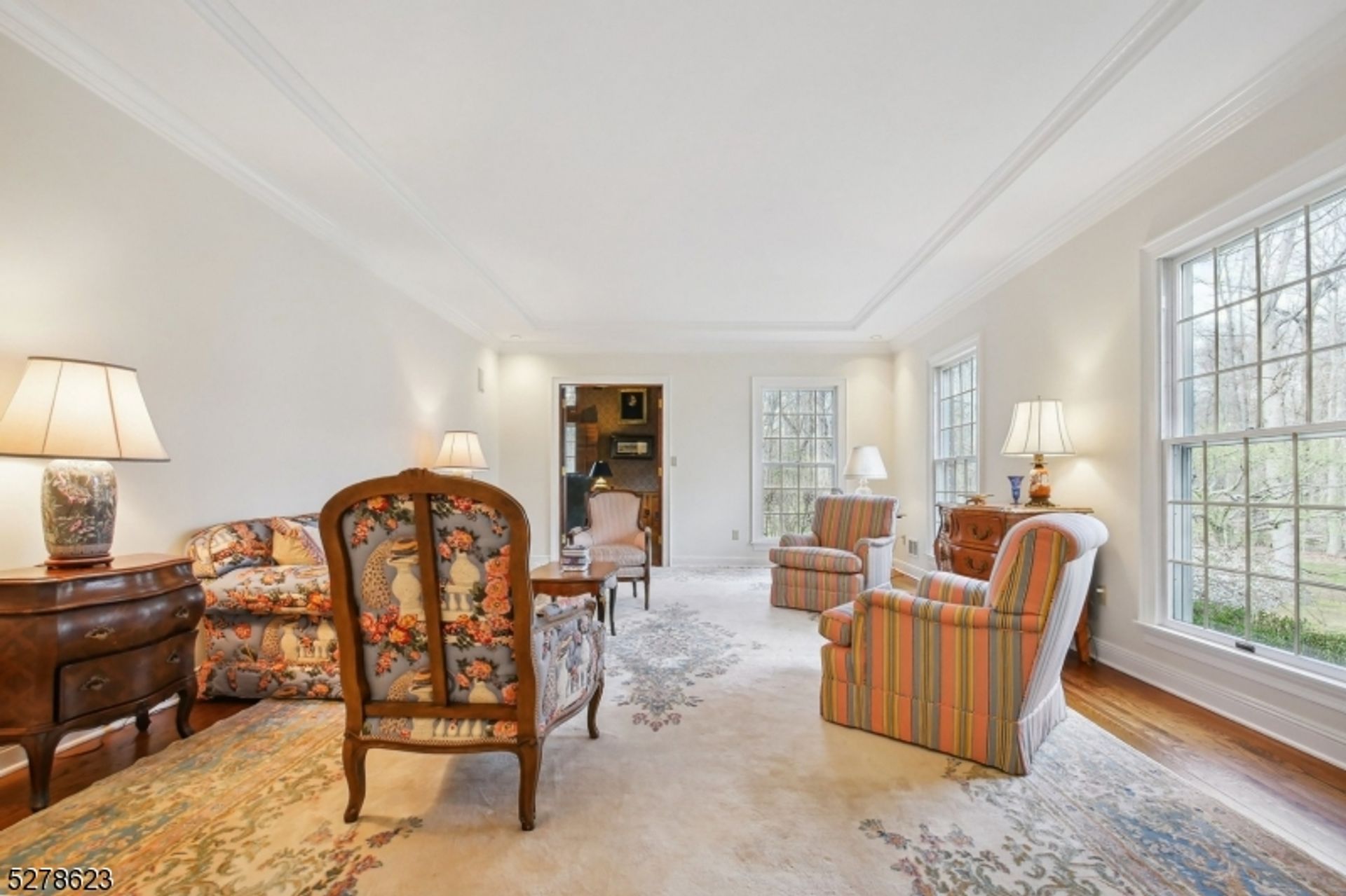 Bright and inviting sitting room with large windows, elegant furniture, and detailed area rugs.