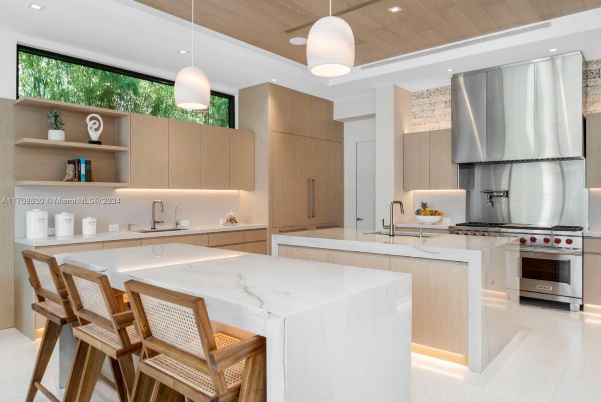 Sleek kitchen featuring light wood cabinetry, dual islands, and a stainless steel range.