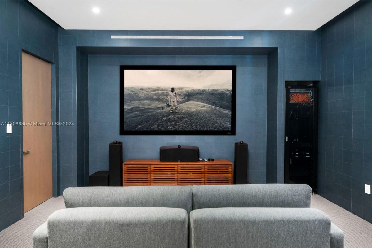 Private home theater with a wall-mounted screen, surround sound system, and comfortable seating.