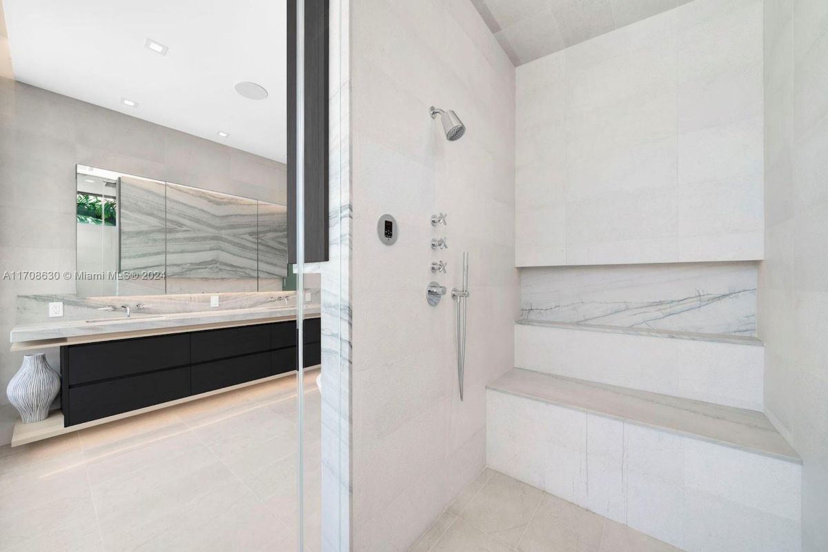 Spacious walk-in shower with marble detailing, built-in bench seating, and contemporary fixtures.