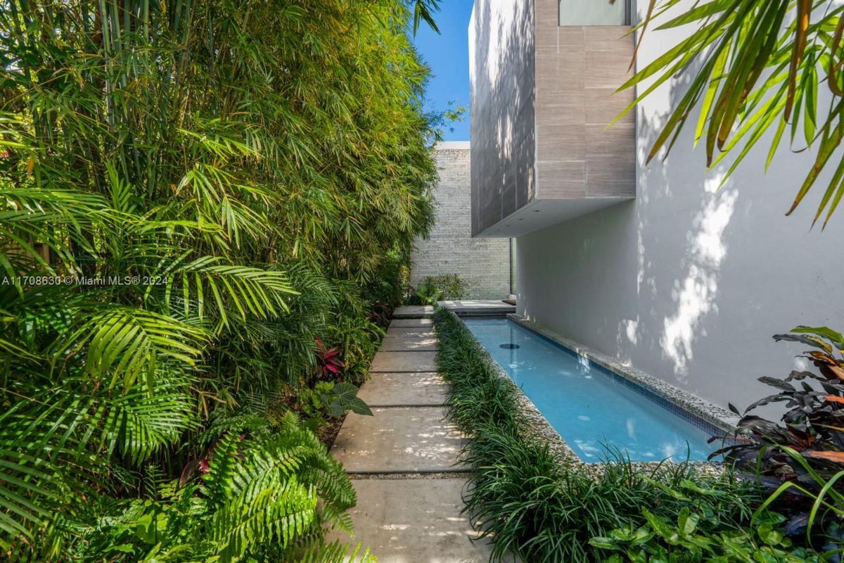 Tranquil walkway lined with lush greenery and a serene water feature.