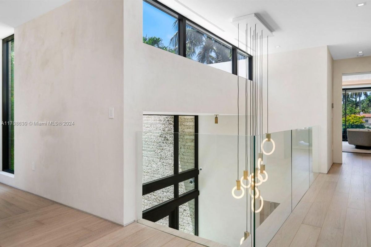 Modern staircase landing with glass railings, minimalist lighting, and floor-to-ceiling windows.