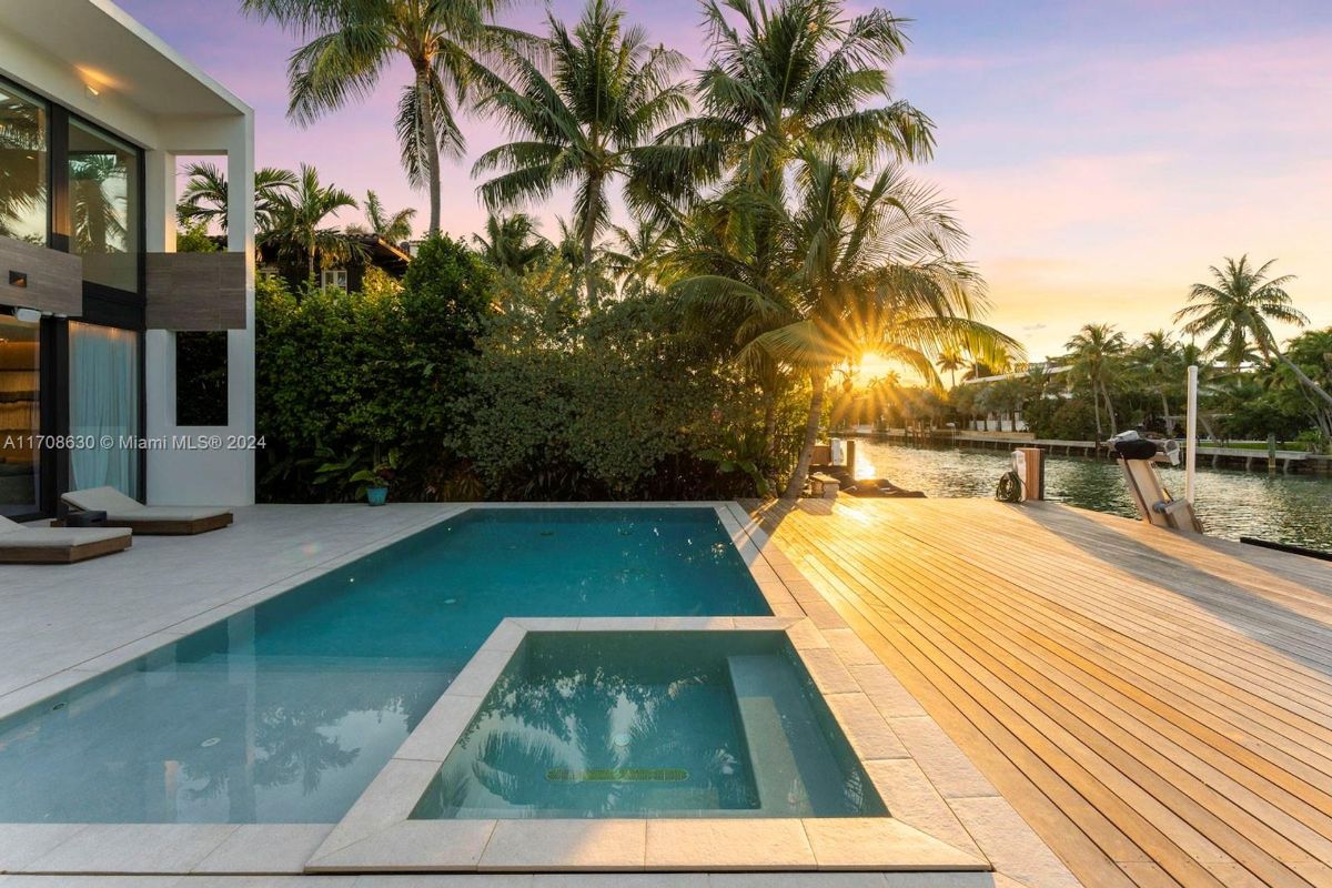 Sunset over the private pool and dock framed by lush tropical landscaping.