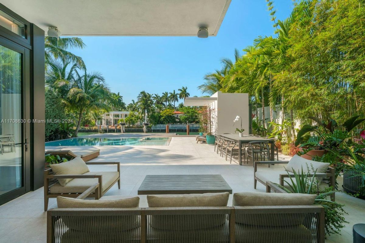 Spacious poolside seating area with views of tropical landscaping and a serene canal backdrop.