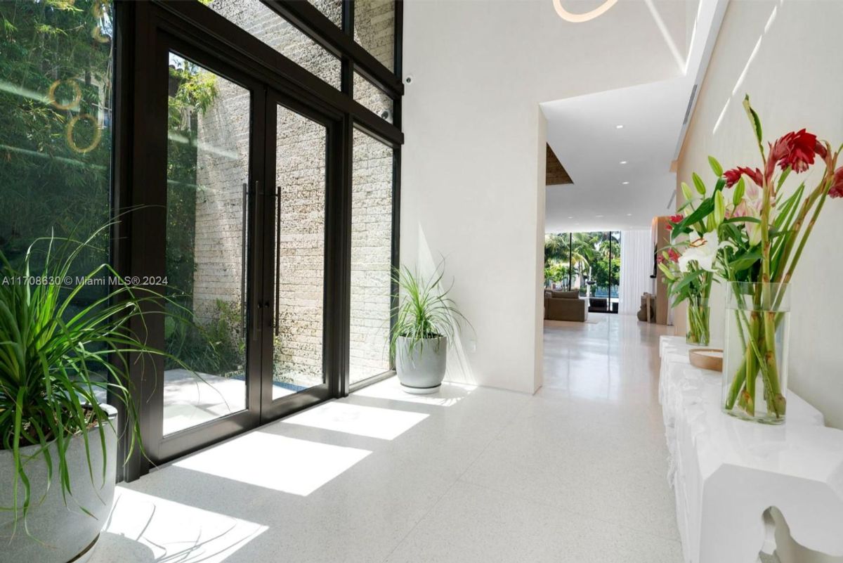 Modern double-door entry framed by tall windows and accented with a tranquil water feature.