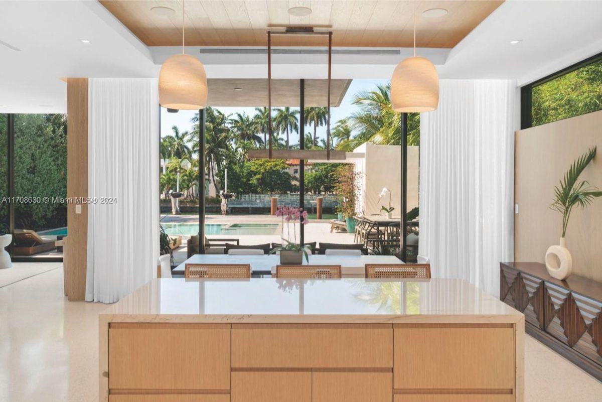 Dining area with a serene poolside view framed by floor-to-ceiling windows.