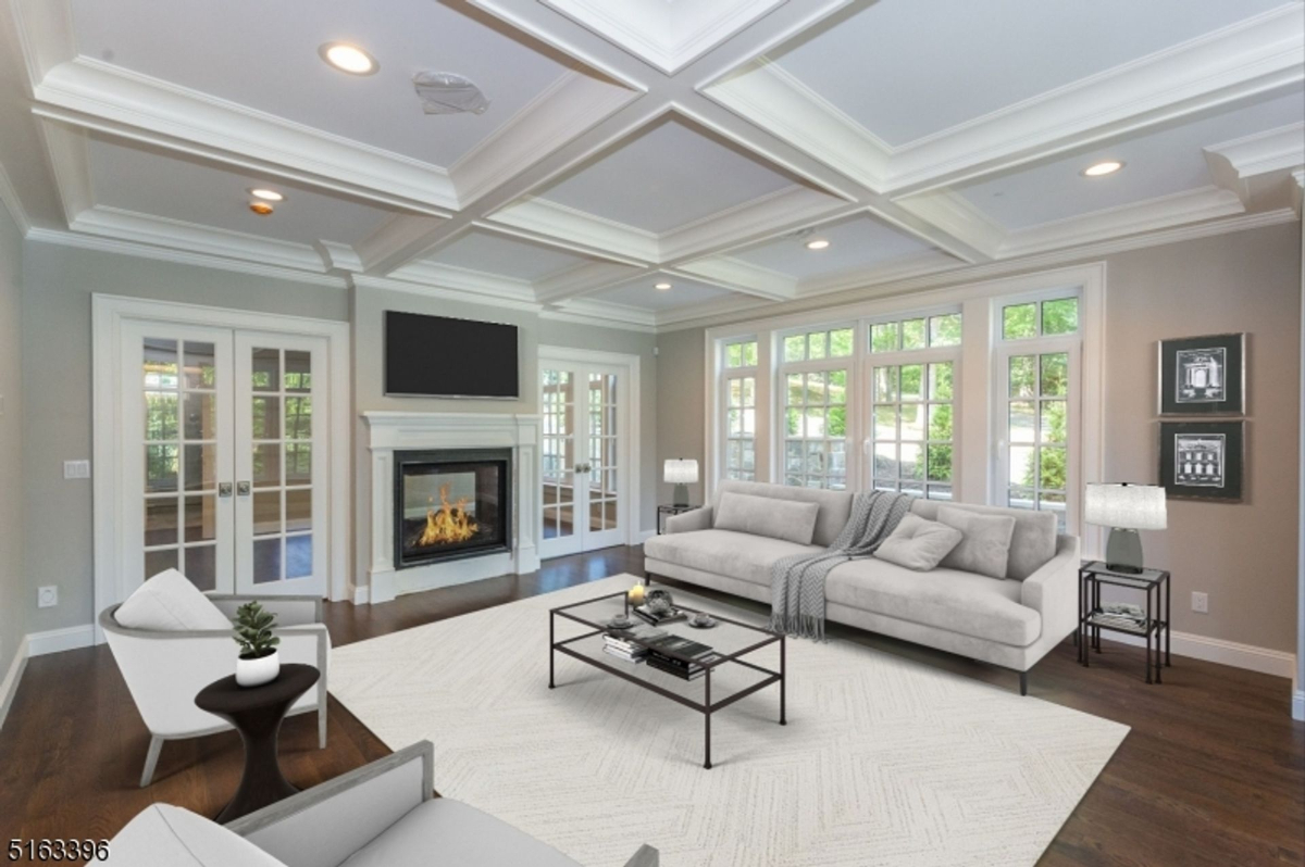 Elegant family room showcasing a coffered ceiling, cozy fireplace, and abundant natural light streaming through large windows and French doors.