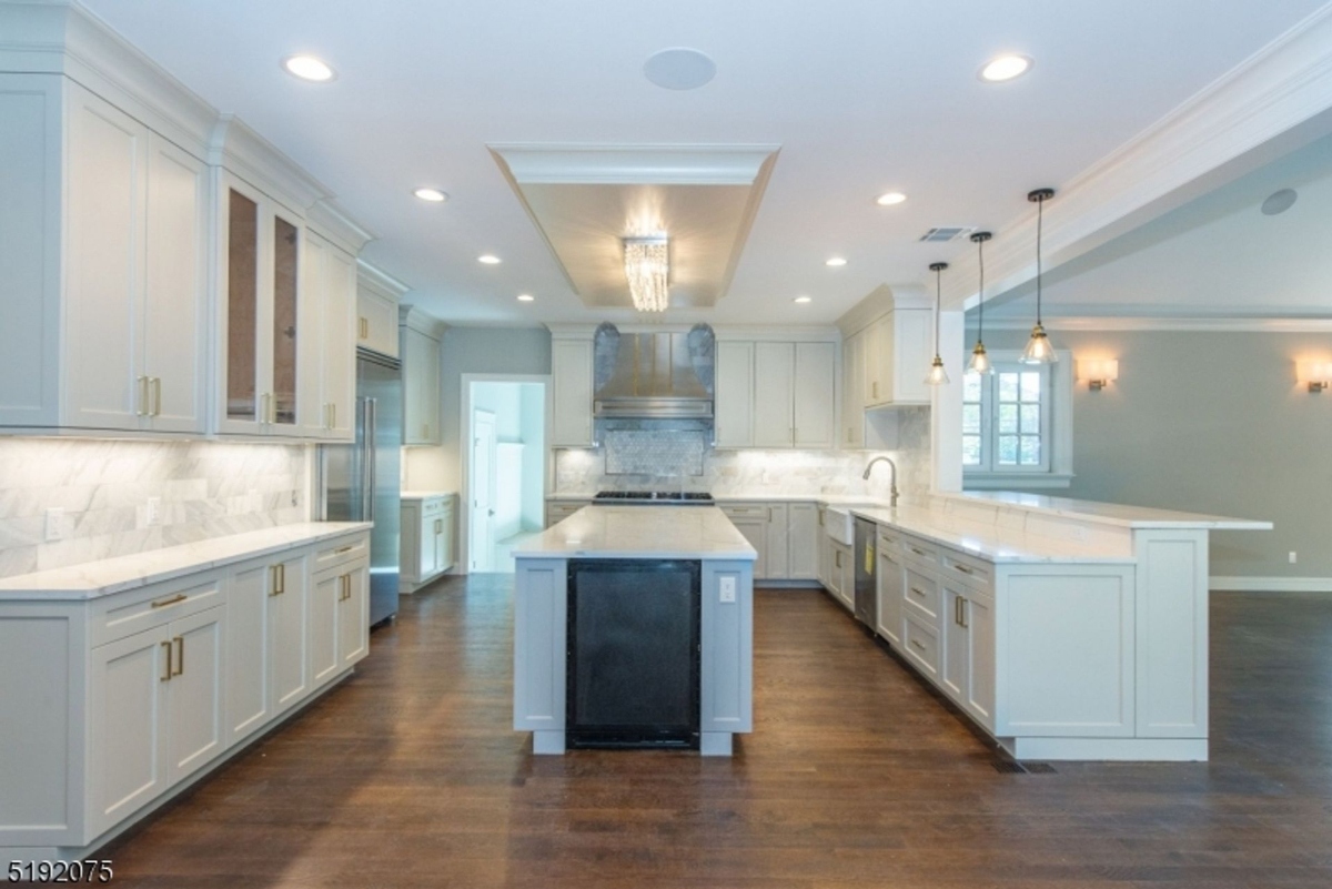 Expansive chef's kitchen features marble countertops, dual islands, pendant lighting, and custom cabinetry with gold hardware.