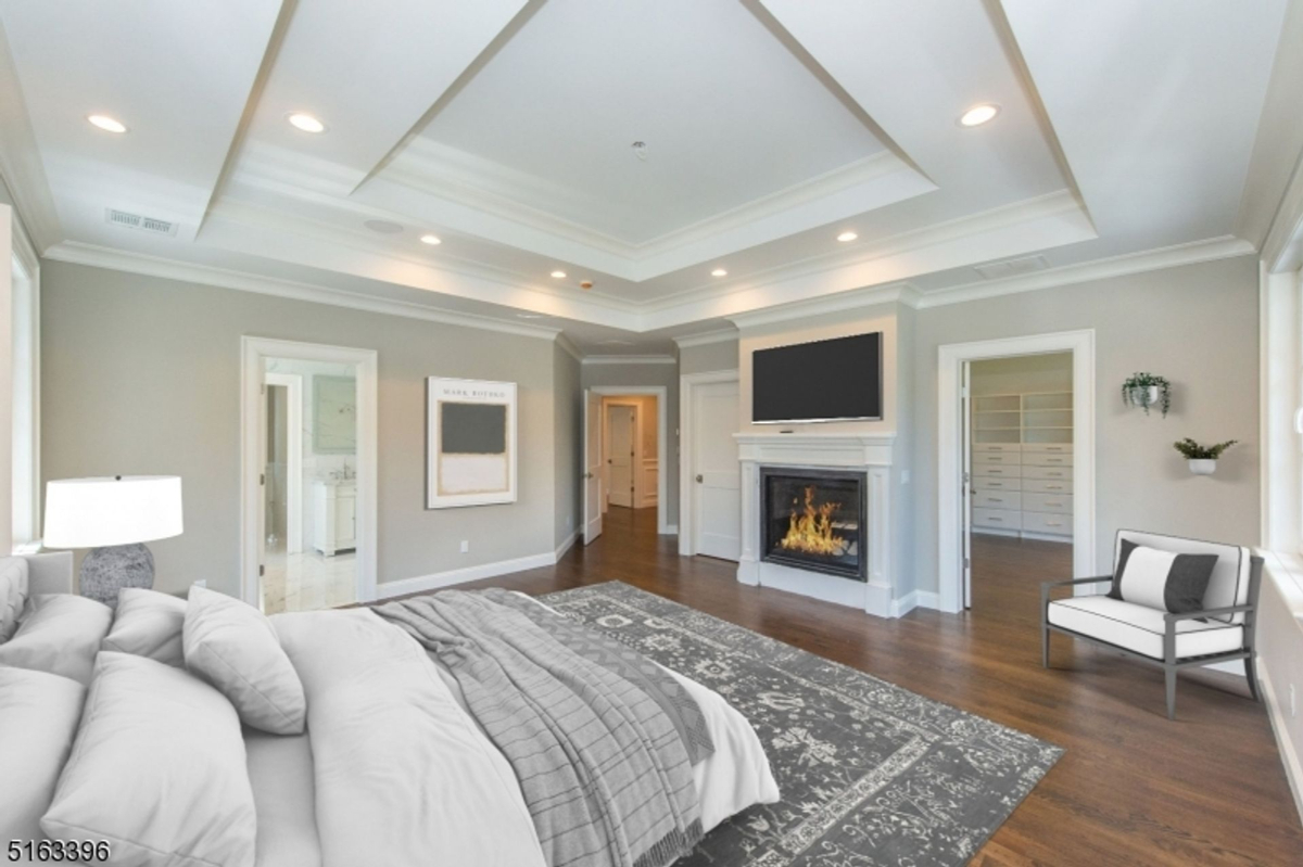 Spacious primary suite showcases a cozy fireplace, tray ceiling, and a walk-in closet with custom built-ins.