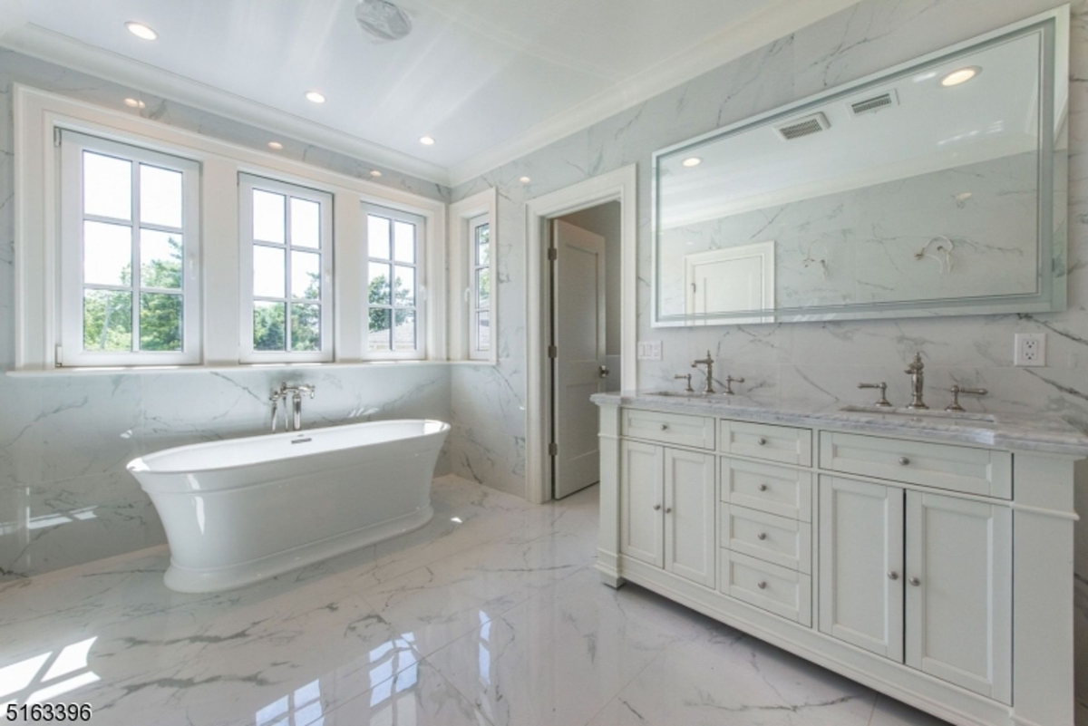 Luxurious bathroom showcases a freestanding soaking tub, marble finishes, and a double vanity with elegant fixtures.