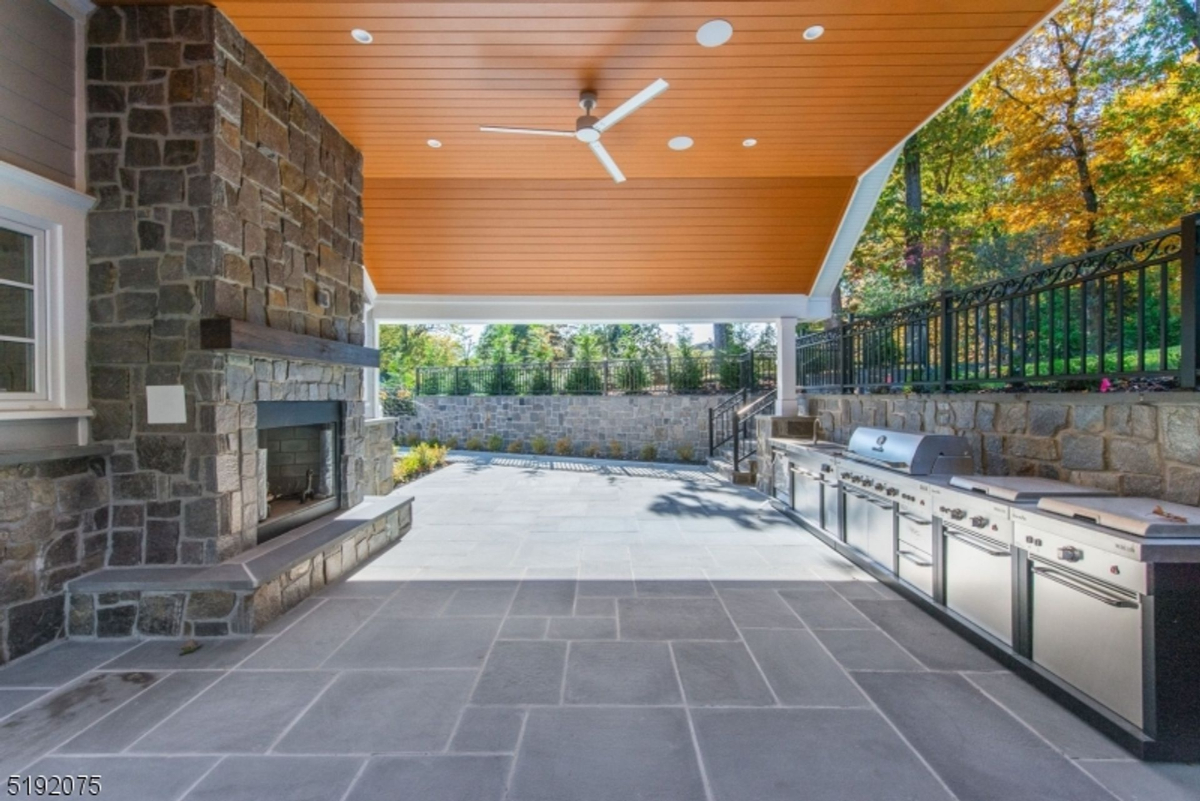 Outdoor entertaining area with a stone fireplace, built-in grill, and spacious seating options.