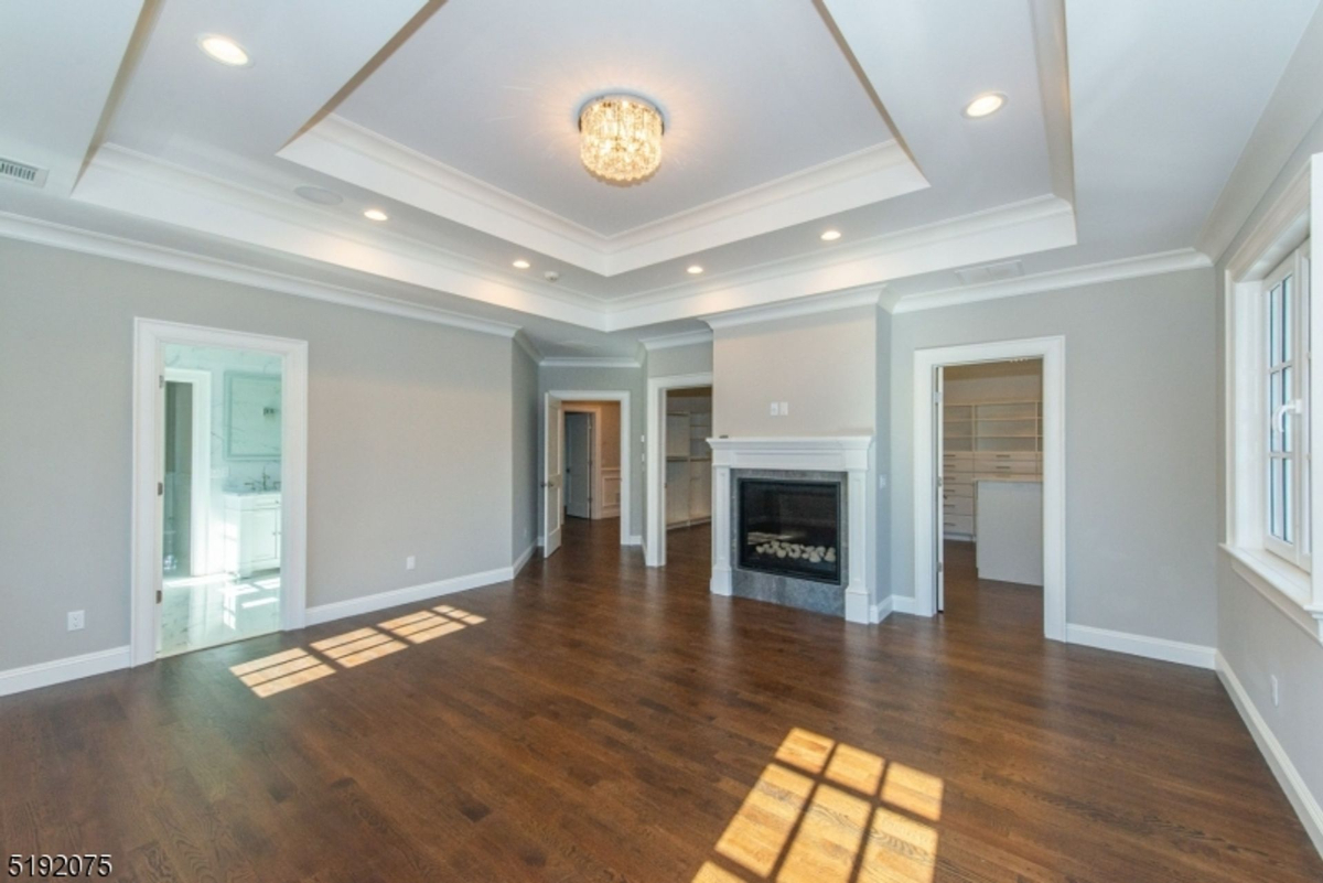 Tray ceiling crowns the expansive primary suite, featuring a cozy fireplace and abundant natural light.