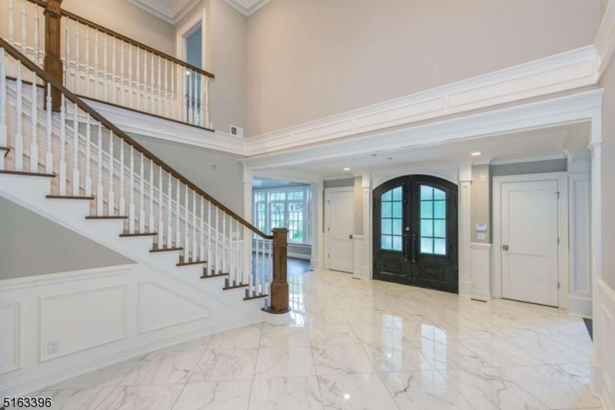 Grand foyer featuring marble floors, a double-door entry, and an elegant staircase.