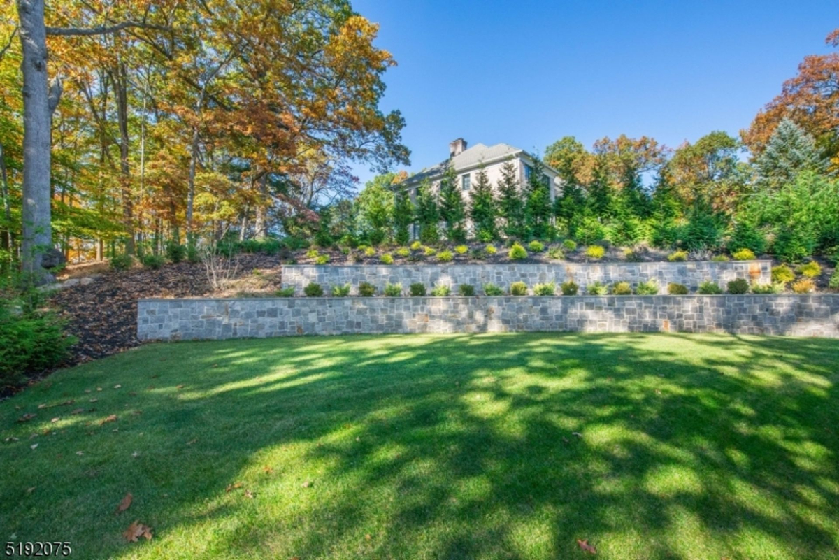 A terraced backyard with lush landscaping, stone retaining walls, and a peaceful wooded backdrop.