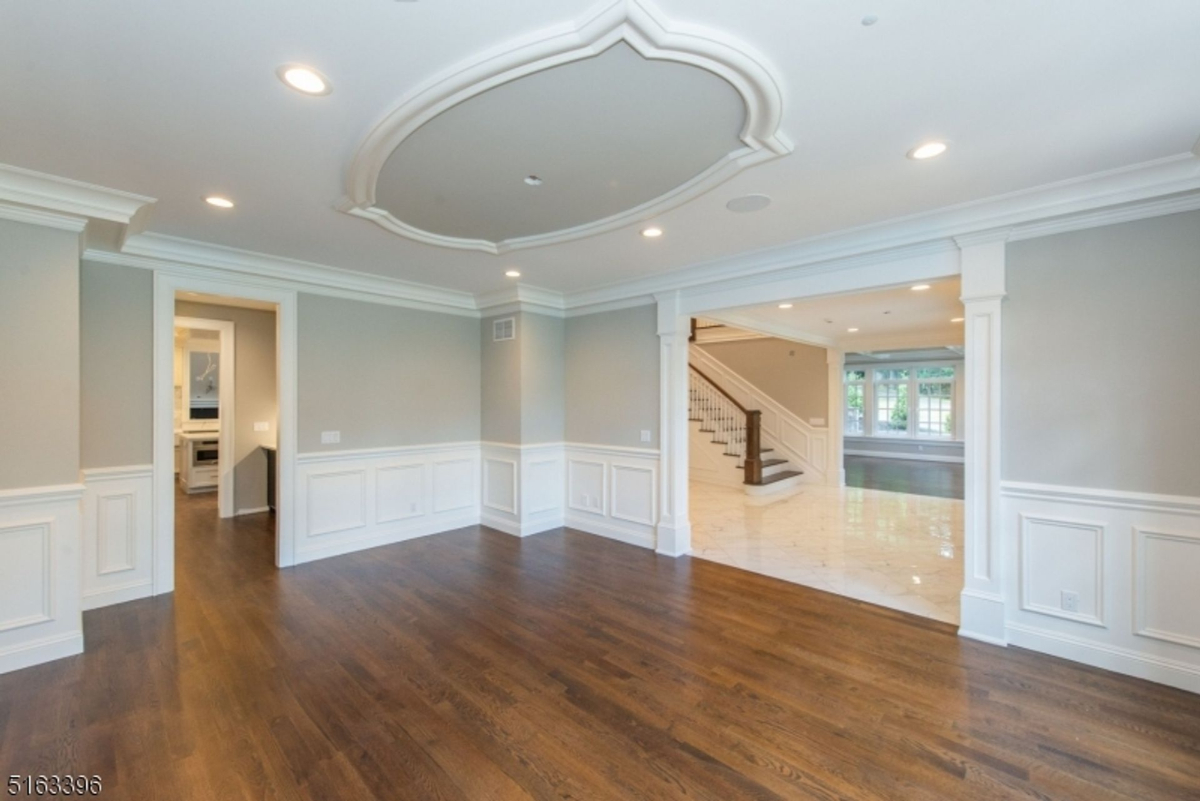 Elegant dining space featuring custom wainscoting, hardwood floors, and intricate ceiling detail.