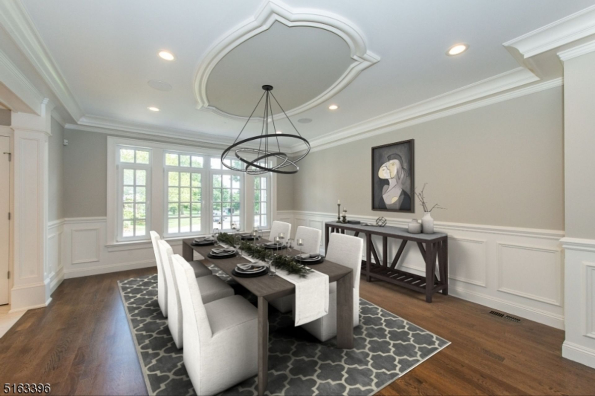 Elegant dining room featuring wainscoting, a coffered ceiling, and large windows that invite natural light.