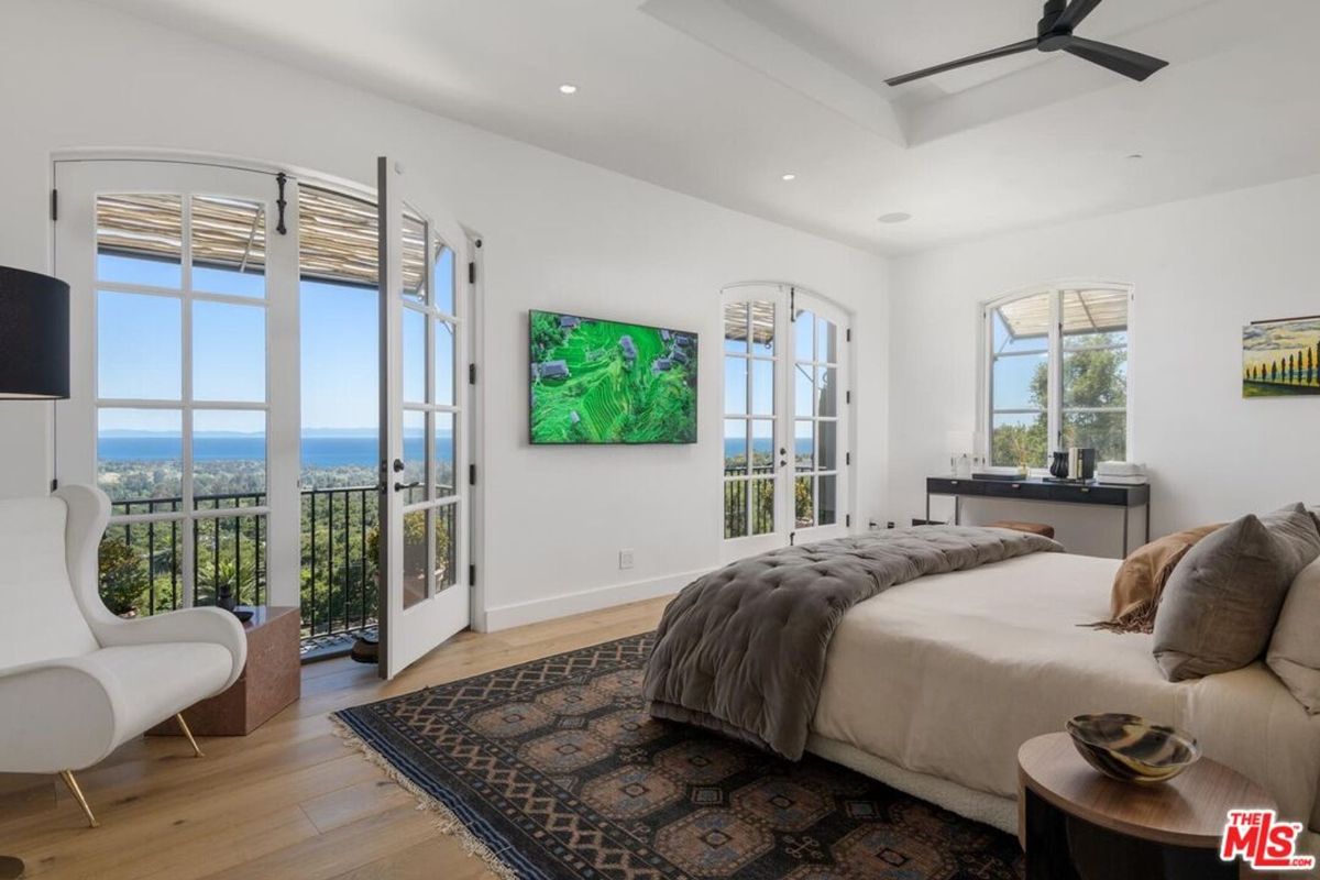 French doors open to a private balcony, offering stunning ocean vistas from this elegant bedroom retreat.