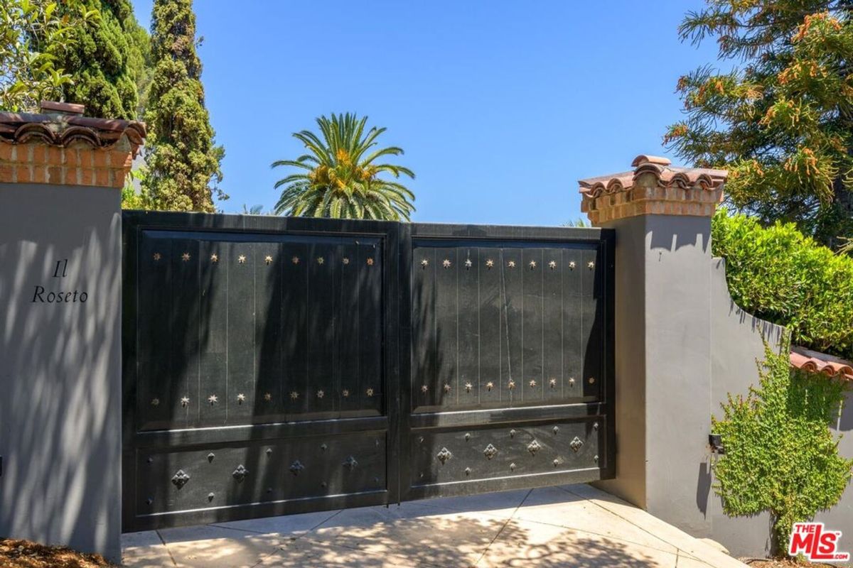 A grand iron gate with intricate details opens to the private estate of Il Roseto.