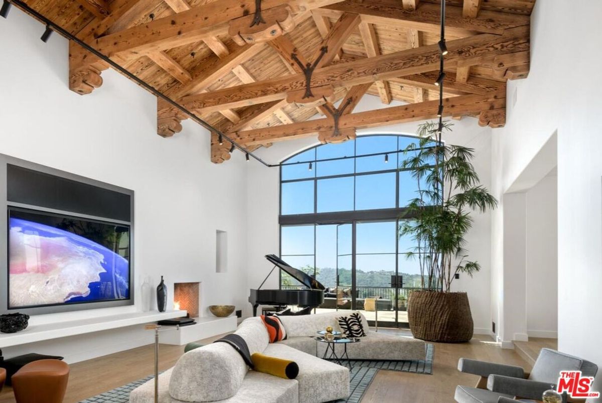 Exposed timber beams and expansive floor-to-ceiling windows complement the modern elegance of this airy living space.