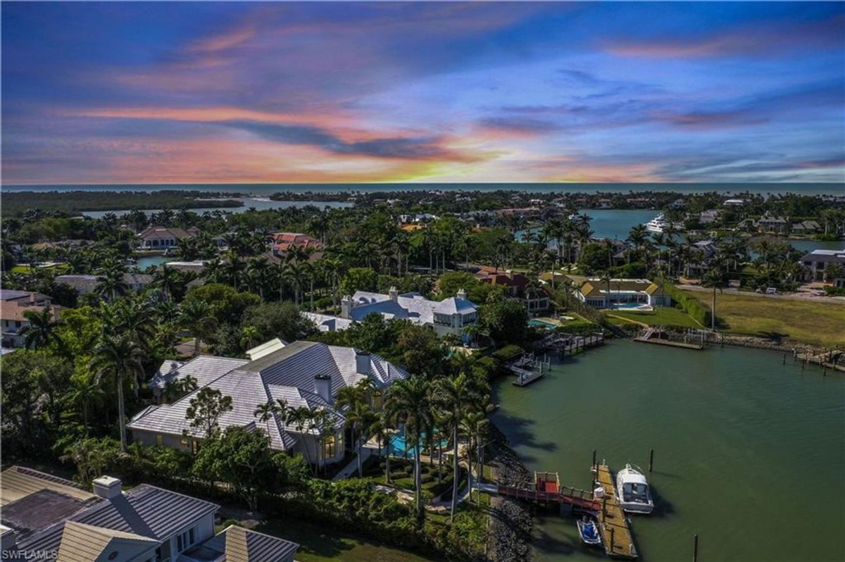 Expansive aerial views reveal a stunning coastal neighborhood, showcasing serene waterways and luxurious estates framed by a glowing sunset.