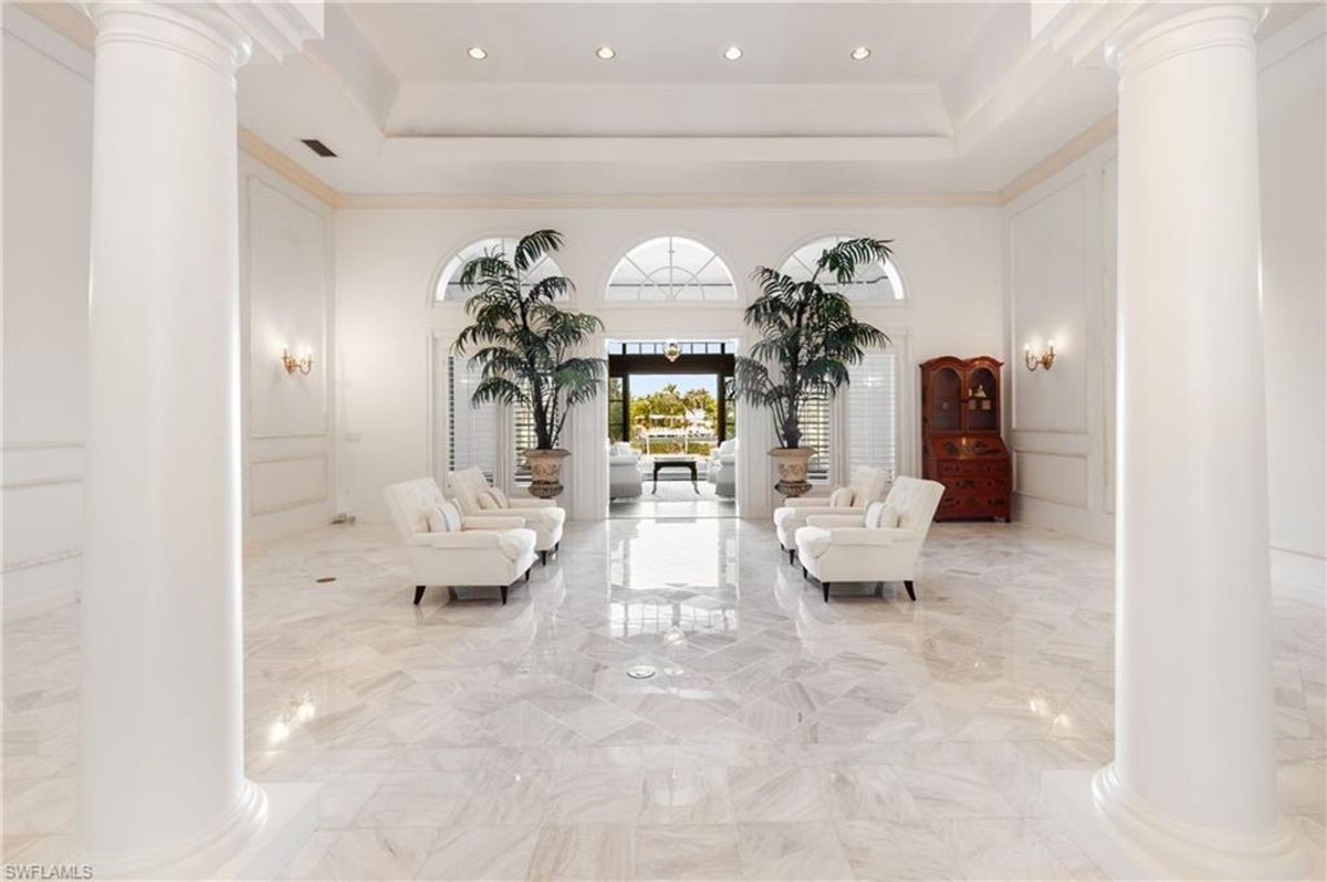 Living space with polished marble floors, towering columns, and arched windows exudes timeless luxury and sophistication.