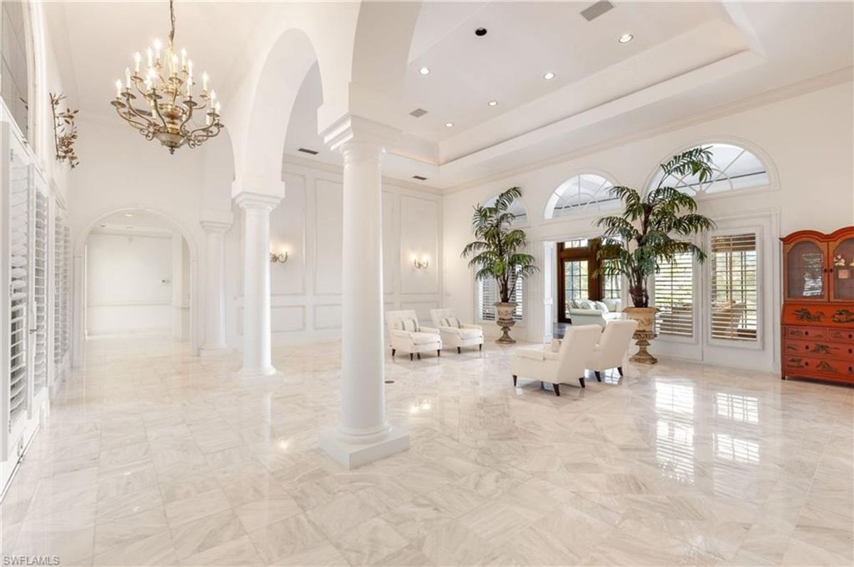 Elegant hall adorned with towering columns, arched openings, and shimmering marble floors creates a refined and inviting atmosphere.