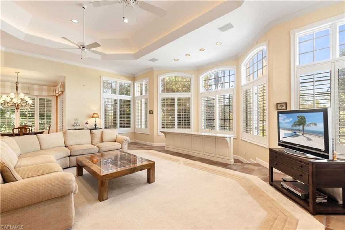 Bright and spacious family room showcases expansive arched windows, recessed lighting, and a comfortable seating arrangement perfect for relaxation and entertainment.