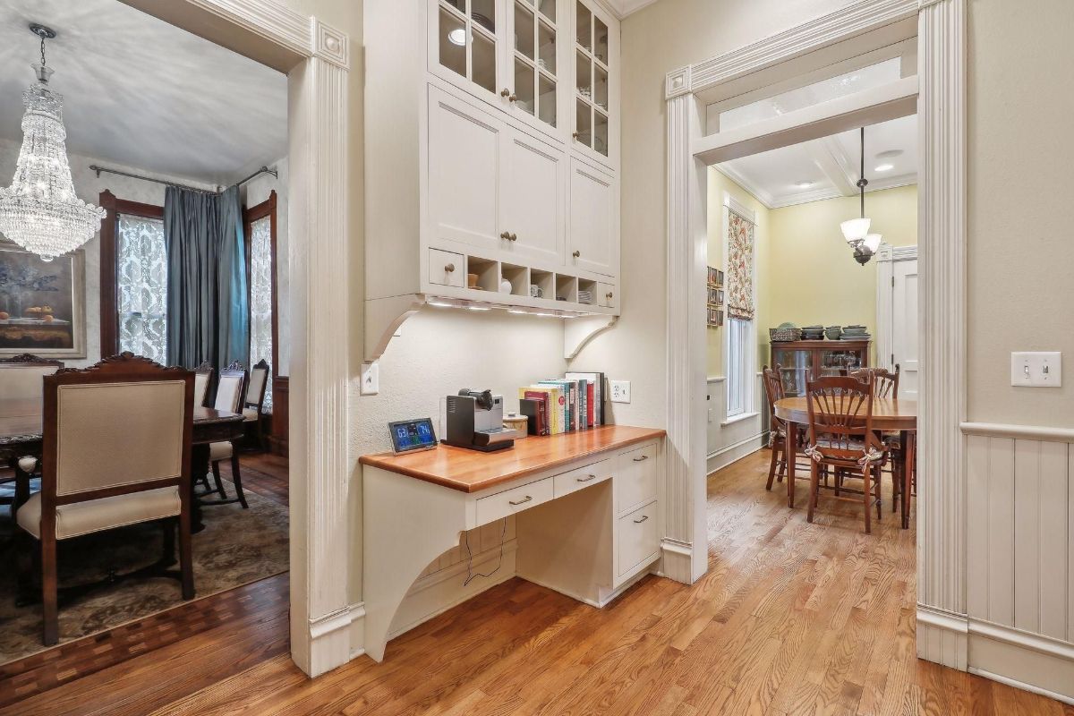 Built-in cabinetry and a desk create a home office space between the dining room and another room.